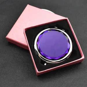 Detailansicht des violetten Kristall-Kompaktspiegels in rosa Geschenkschachtel mit Samt.