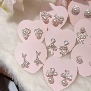 Detailed view of sweet heart-shaped pink cards displaying dainty pearl and zircon earrings.