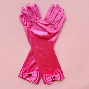 Detalle de guantes brillantes de satén rosa para niños con lazo elegante y cristal.