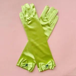 Vista detallada de los guantes de satén verde para niños con un lazo elegante y una gema.