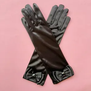 Vista detallada de guantes largos de satén negro con lazos elegantes y brillantes pedrerías.