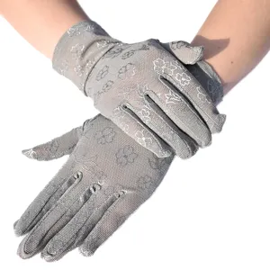 Nahaufnahme von atmungsaktiven grauen Spitzenhandschuhen mit filigranem Kleeblattmuster.