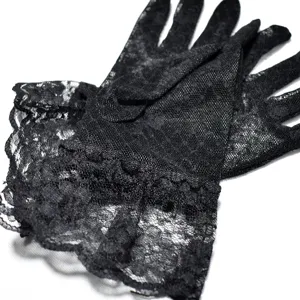Detailaufnahme schwarzer Spitzenhandschuhe mit feinem Netzmuster und eleganter Rüschenborte.
