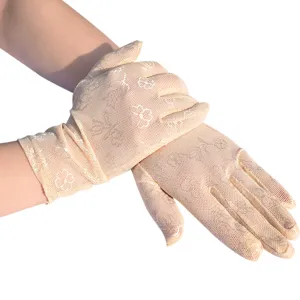 Nahaufnahme von beige spitzigen Netz-Sonnenschutzhandschuhen mit filigranem Kleeblatt-Muster.