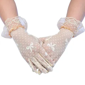 Detailaufnahme von beigen Vintage-Spitzenhandschuhen mit Schleife und zarten Rüschen im Sommer.