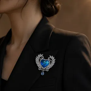 Prachtige blauwe hart kristallen broche met delicate blad filigraan en sprankelende stenen.