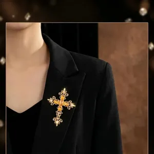 Nahaufnahme der goldenen Vintage-Kreuzbrosche mit gelben Steinen und Strass am schwarzen Blazer.