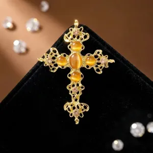 Detailaufnahme der Vintage Goldlegierung Kreuz Brosche mit bernsteinfarbenen Katzenaugen und Strass.