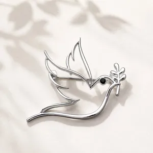 Detailed shot of a minimalist hollow dove bird brooch with olive branch in silver finish.