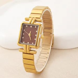 Detailaufnahme der eleganten goldenen Uhr mit braunem Zifferblatt und Metallarmband.