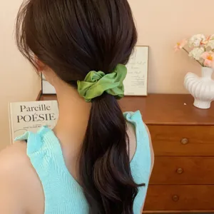 Vista detallada de coletero de seda verde para el pelo, elegante accesorio moda.