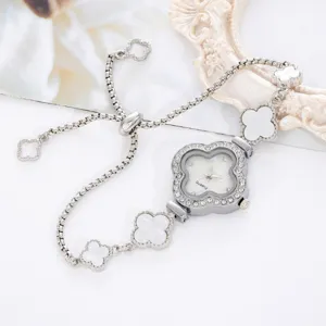 Detailed close-up shot of elegant silver four-leaf clover quartz watch with rhinestone bezel.