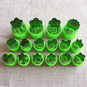 Details van roestvrijstalen groentesnijder met diverse vormen en groene handgrepen.