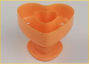 Close up detail view of the orange heart shaped baking mold highlighting its hollow design.