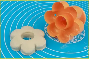 Orange plastic flower-shaped baking mold and dough cutter for making donuts and pastries.