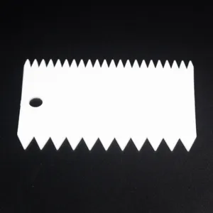 Close-up detail of white plastic serrated cake scraper and dough cutter for baking tool use.
