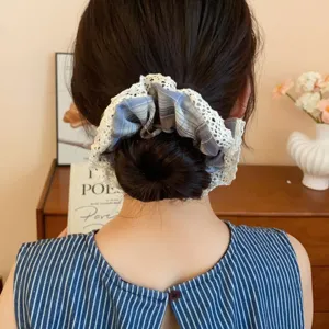 Detailed view of the vintage plaid fabric hair scrunchie with delicate white lace trim.