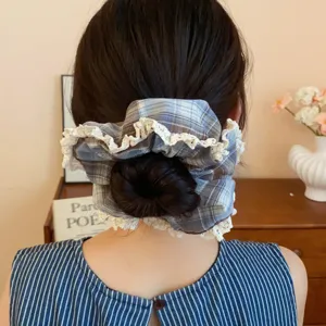 Detailed view of brown plaid hair scrunchie with delicate white lace trim for elegant hairstyles.