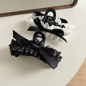 Detail view of stylish polka dot hair claw clip with elegant black bow for women and girls.