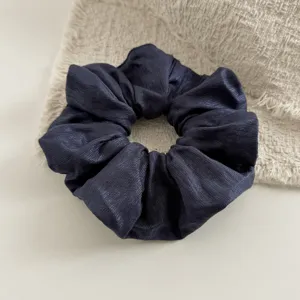 Donkerblauwe satijnen haarelastiek stof detail, elegante geplooide haaraccessoire.