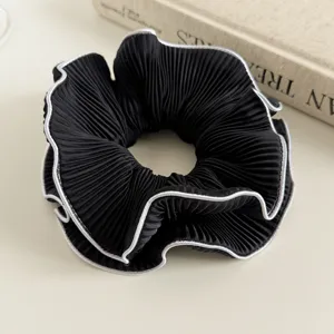 Close-up van zwarte geplooide haarring met zilveren randdetails, elegante accessoire.