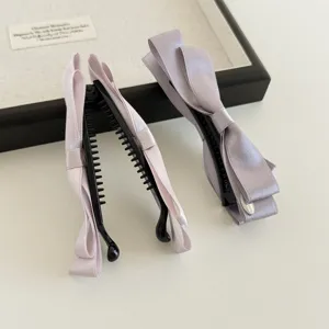 Nahaufnahme eleganter Satin Schleife Haar Bananenclip, glatte Textur und vertikales Design.