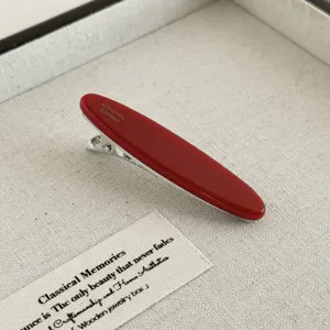 Detailaufnahme der roten Acetat-Haarspange mit glänzender Oberfläche und stabiler Metallklammer.