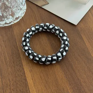 Zwart-wit gestipte telefoonkoord haarelastiek detail, flexibel elastisch haaraccessoire.