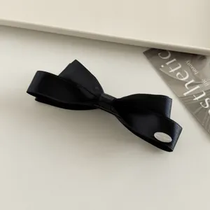 Detailaufnahme der schwarzen Satin Schleife Haarklammer mit Metallplatte, elegante Spange.