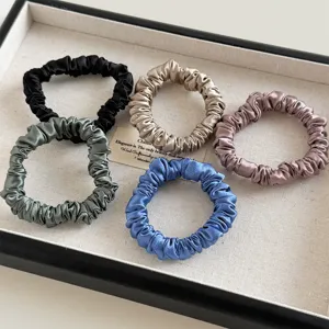 Set mit fünf farbenfrohen Satin-Haargummis in verschiedenen Farben, stilvoll präsentiert.