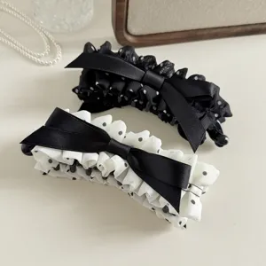 Detailed shot of Korean polka dot pleated bow banana hair clip, elegant black and white design.