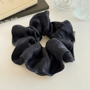 Grote zwarte satijnen scrunchie detailweergave, glanzend geplooide haarelastiek voor dames.