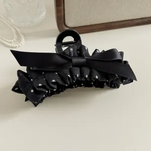 Close-up detail of black polka dot bow hair claw clip, elegant fabric hair accessory.