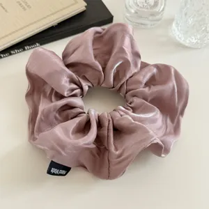 Gedetailleerd overzicht van een elegante glanzende satijnen haarelastiek in mauve met label.