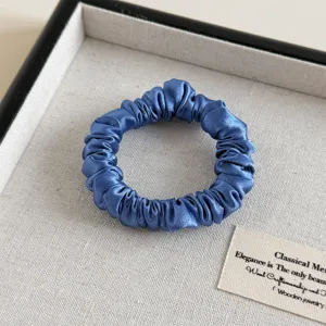 Detailaufnahme des blauen Satin-Haargummis, elegante Textur und glatte Oberfläche für Frauen.