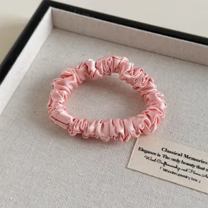 Nahaufnahme eines weichen rosa Satin-Haargummis, der feine Textur und elegantes Design zeigt.