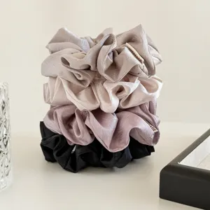 Detailopname van zachte satijnen haarelastiekjes in elegante neutrale tinten, gladde textuur.