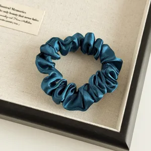 Dunkelblaue Satin Haargummi Detailaufnahme, elegantes Plissee Design für schicke Frisuren.