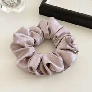 Satijnen scrunchie detail, crème paars haarelastiek, elegant minimalistisch haaraccessoire.