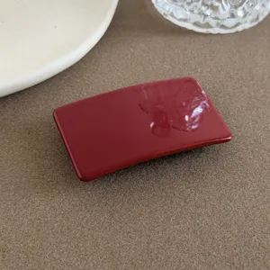 Rote glänzende rechteckige Haarklammer Detailansicht, minimalistisches geometrisches Accessoire.