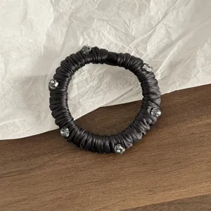Nahaufnahme eines schwarzen Satin-Haargummis, verziert mit glitzernden Kristallperlen.
