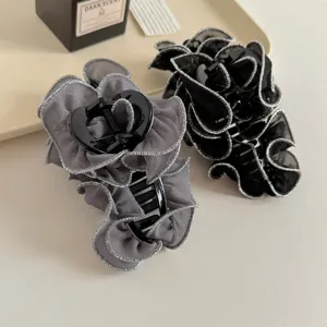 Primo piano di eleganti pinze per capelli in chiffon plissettato grigio e nero con bordo.