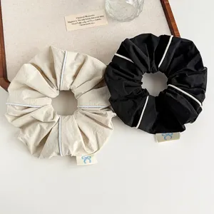 Detail view of minimalist fabric hair scrunchies with white piping and cute bow accent.