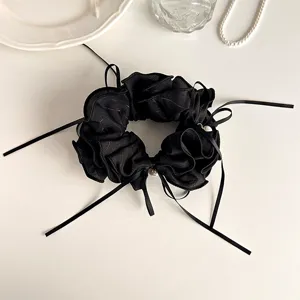 Detailed view of black lettuce edge hair scrunchie with bow ribbon and elegant pearl charm.