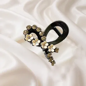 Gros plan détaillé d'une pince à cheveux noire élégante ornée de strass et de fleurs.