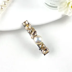 Detailed close-up of a luxury rhinestone and pearl hair clip with sparkling champagne crystals.