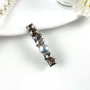 Detailed shot of sparkling rhinestone and pearl decorative hair clip on white surface background