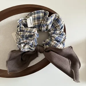 Vue détaillée de chouchou à carreaux fait main avec nœud marron, accessoire en tissu.