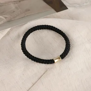 Black braided hair tie with a gold metallic tube detail, elegant and durable design.