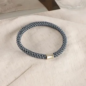 Dark grey woven hair tie with gold metal tube detail, high elasticity and durable daily wear.